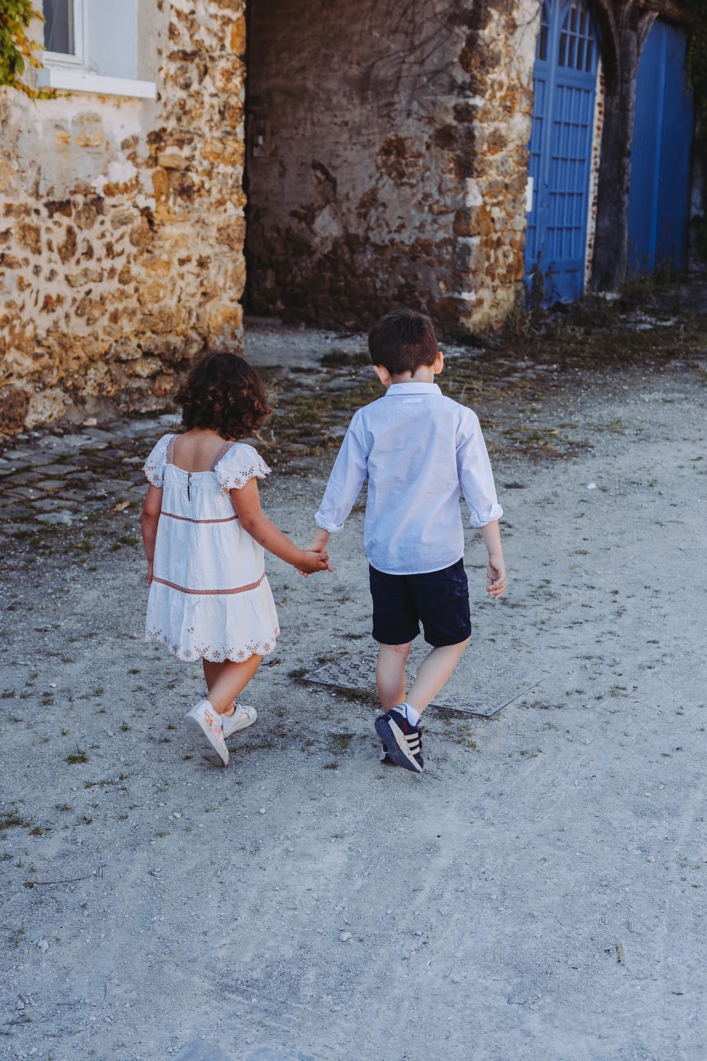 Photographie de 2 enfants de dos qui se tiennent la main en tenue de mariage