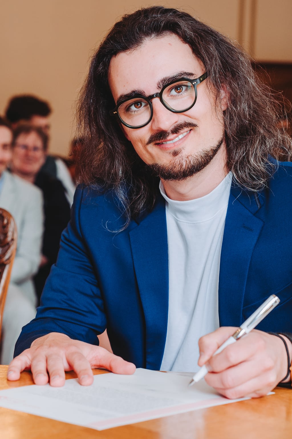 Photographie d'un témoin de mariage en train de signer le registre de la mairie