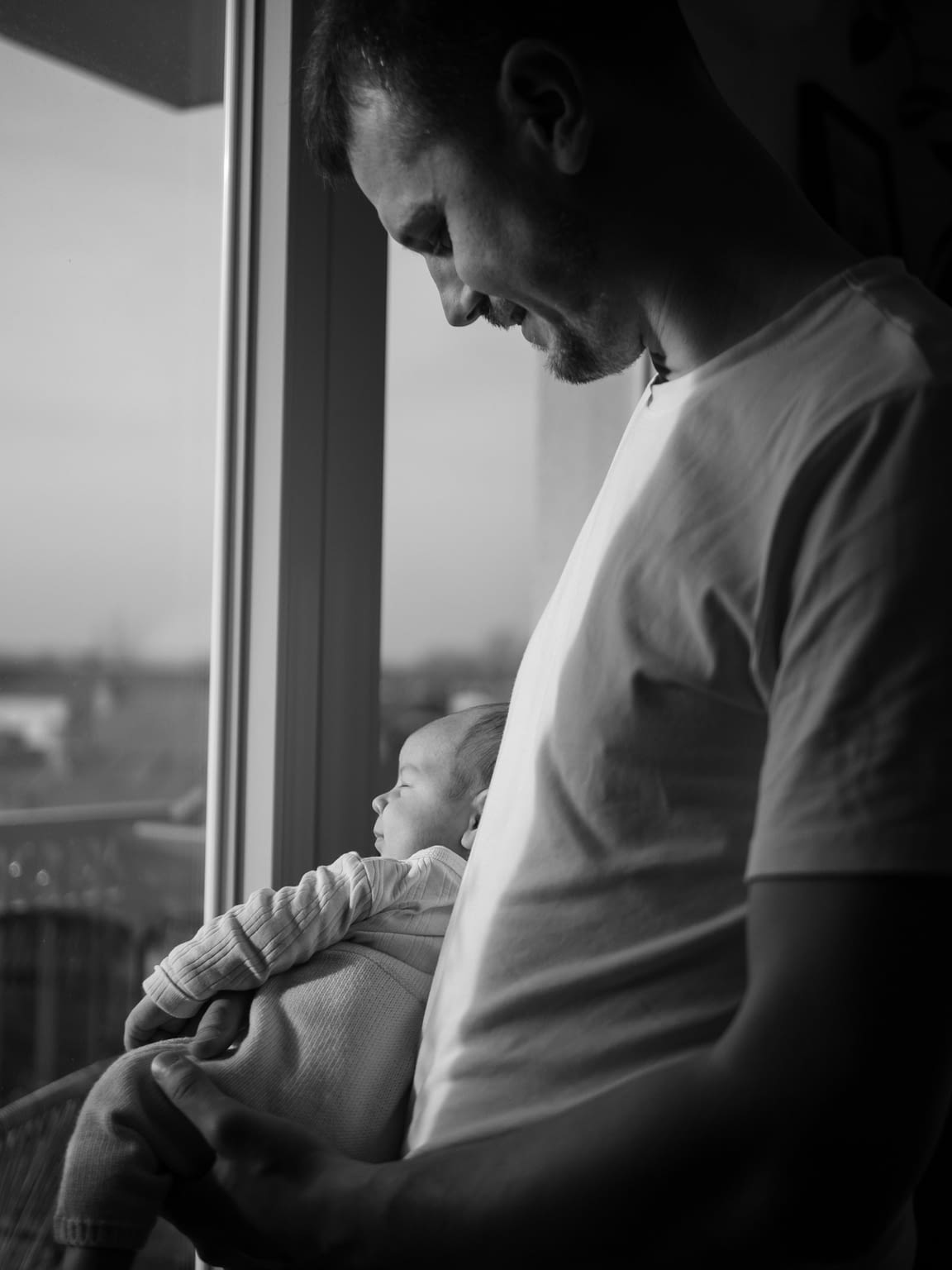 Photographie d'un papa et son bébé face à une fenêtre avec leurs reflets