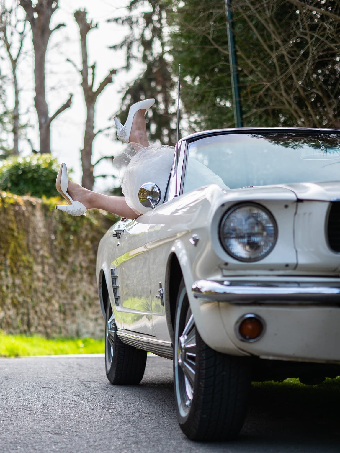 Photographie d'une mustang avec chaussures d'une mariée qui dépassent de la voiture