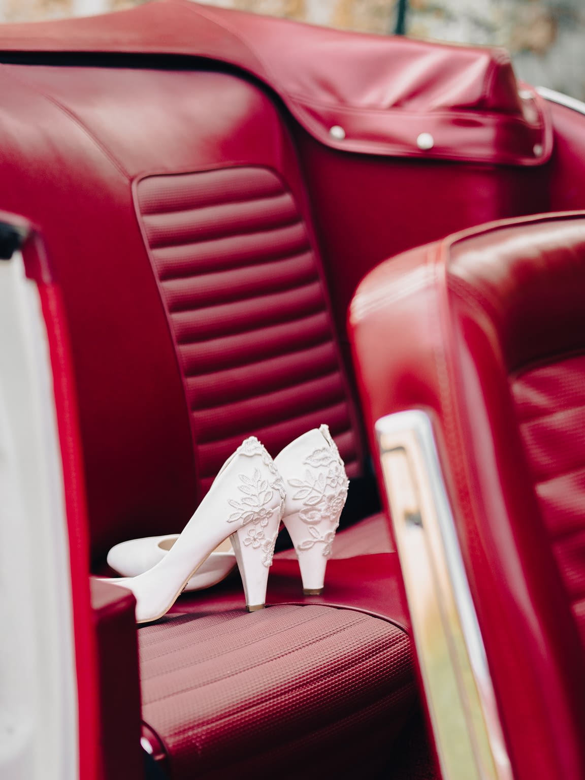 Photographie d'une paire de chaussures de mariée posée sur le siège en cuir d'une voiture mustang ancienne