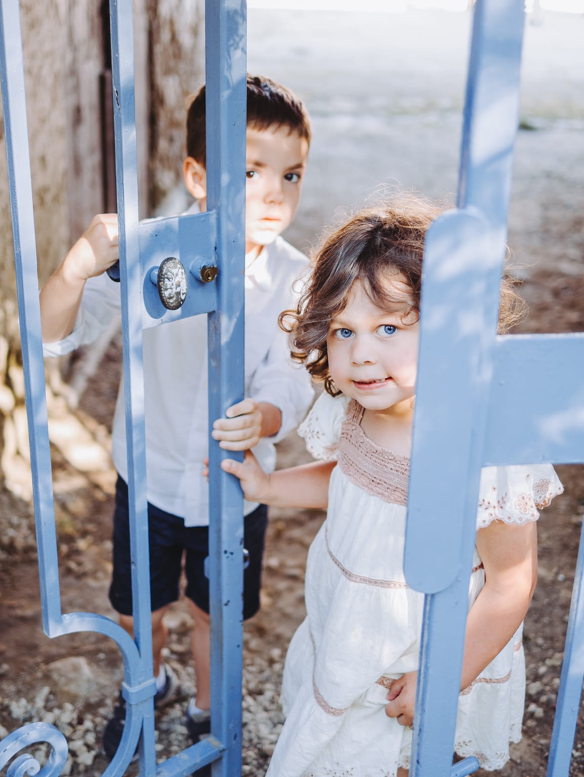 Photographie de deux enfants en train de jouer derrière une grille pendant un mariage