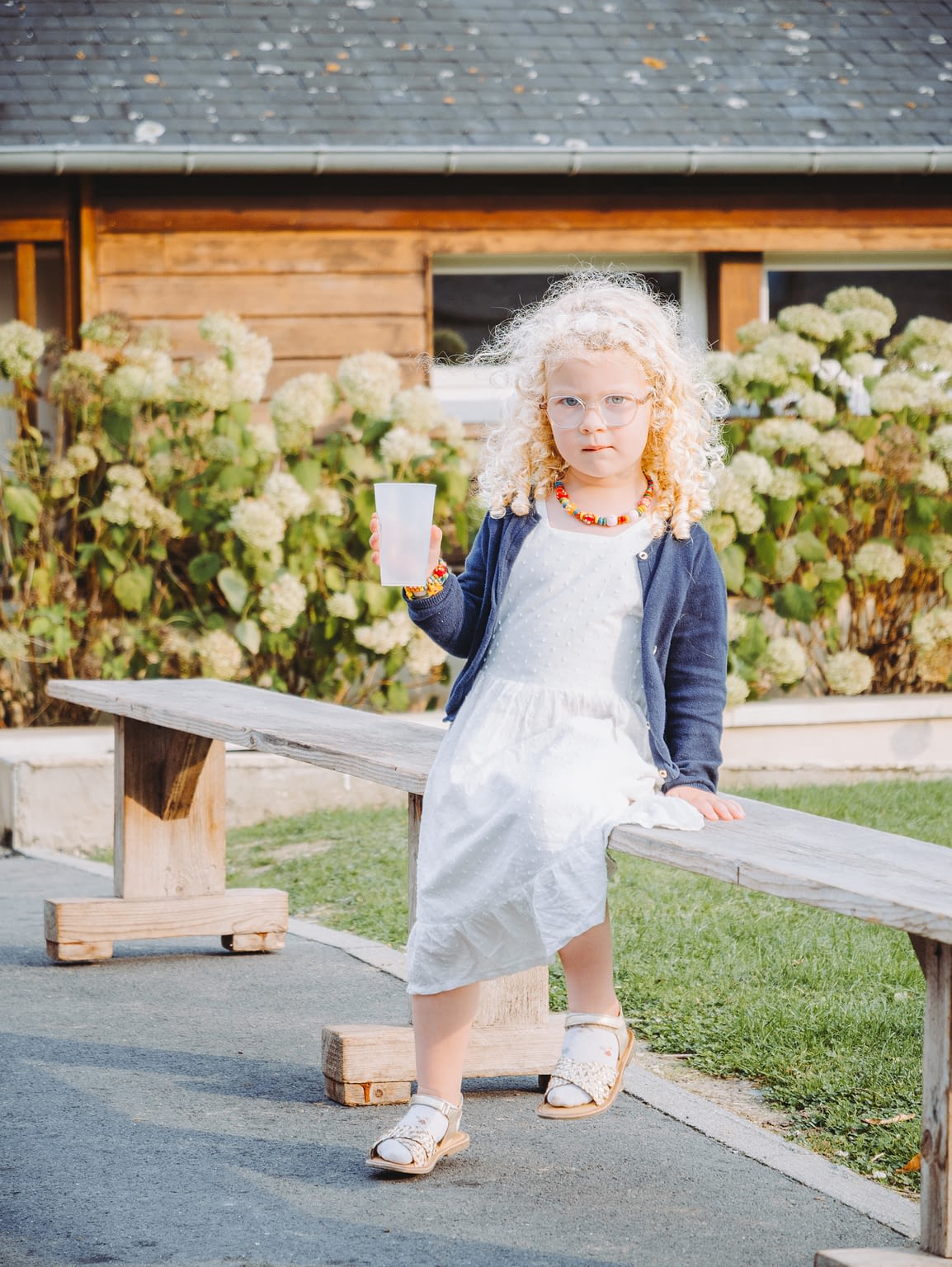Photographie d'une petite fille lors d'un mariage qui tient un verre d'eau en faisant la moue