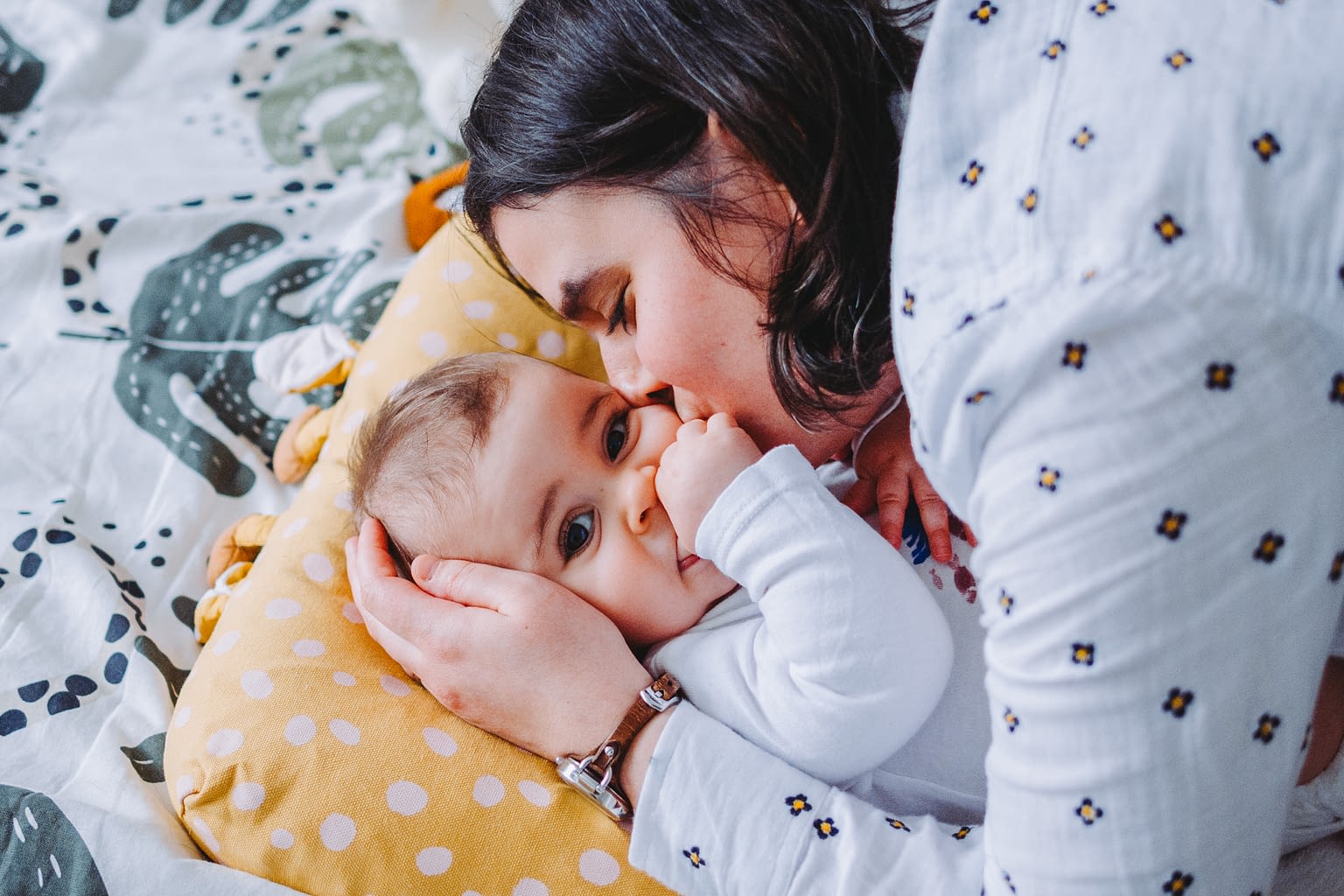 Photographie d'une maman qui fait un bisou à son bébé sur le lit